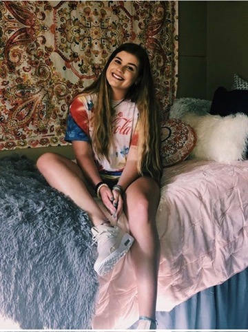 Brooke on her freshman move-in day, sitting on her dorm bed